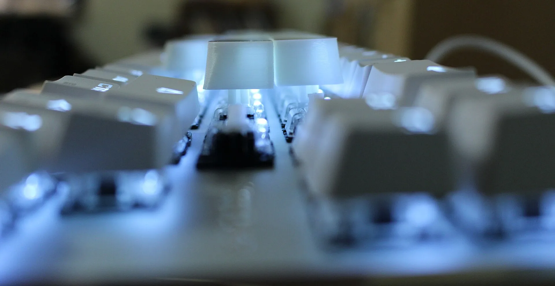 Mechanical keyboard close-up with white keycaps and blue LED backlight glow